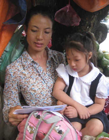 Nữ vận động viên khuyết tật kiểm tra lại vở học bài của con gái. Ảnh: Hoàng Phương.