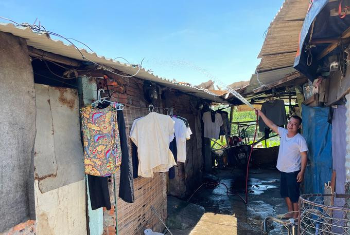 Một người bán hoa quả ở xóm trọ sau chợ Long Biên phun nước lên tấm chăn trên mái để có thể ngủ vài tiếng buổi trưa. Anh cho biết ngày phun hai lần trưa và tối. Ảnh: Phan Dương.