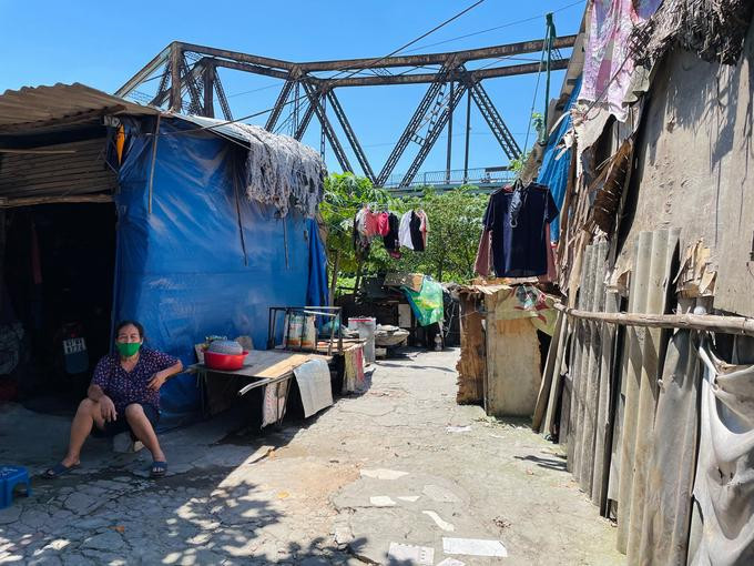 Bà Lĩnh ngồi mé hiên hàng xóm lúc 11h trưa ngày 18/6 trong ngụ cư dưới chân cầu Long Biên. Nhà của bà là căn quây tôn bên phải. Ảnh: Phan Dương.