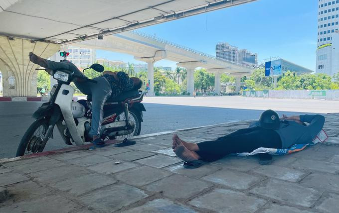 Người lao động chợp mắt trưa 19/6 dưới gầm cầu vượt, trong cái nắng nóng gay gắt trên 40 độ C. Ảnh: Phan Dương.