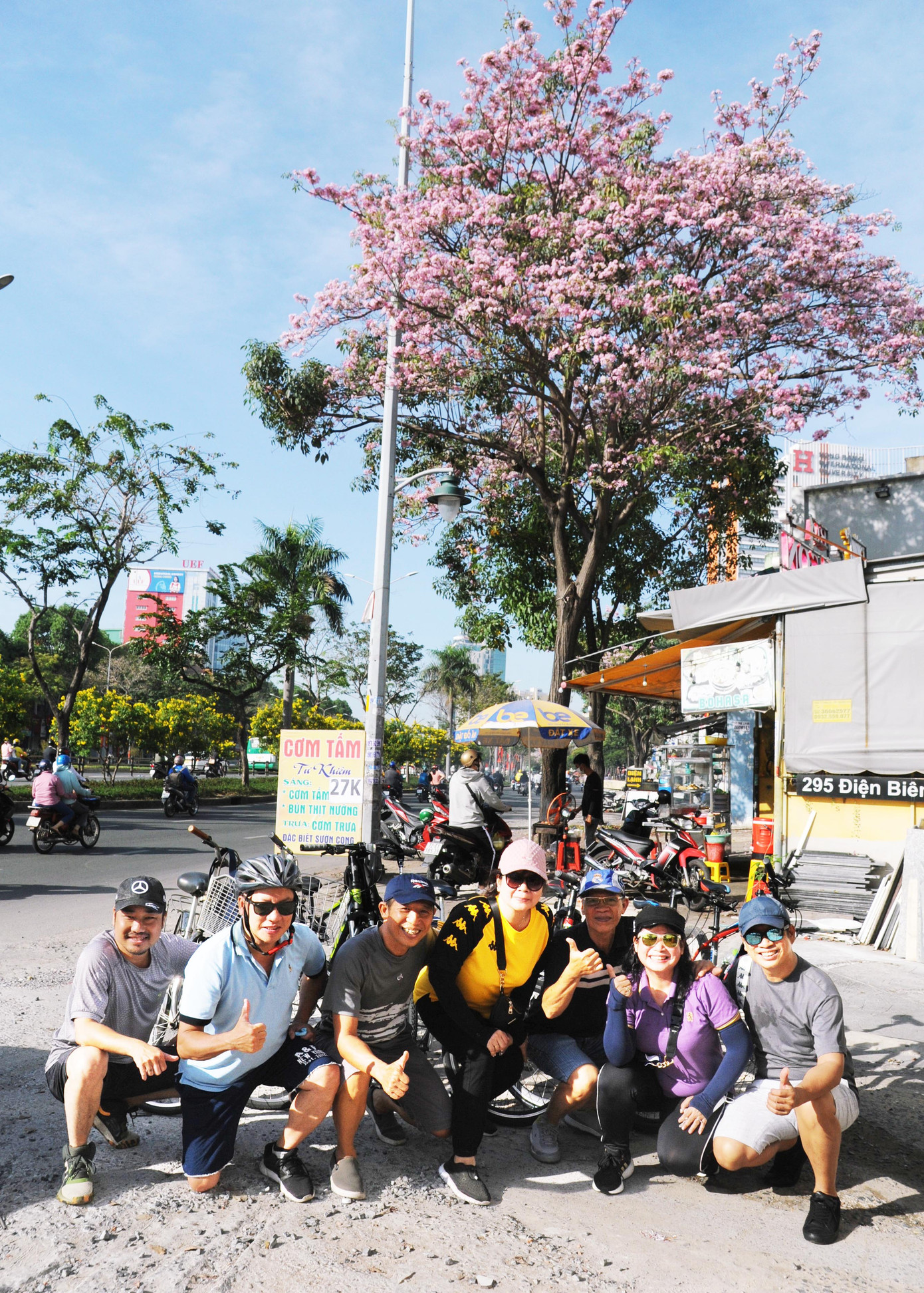 Các thành viên một câu lạc bộ xe đạp ở quận Phú Nhuận chụp ảnh với hàng cây kèn hồng nở hoa rực rỡ.