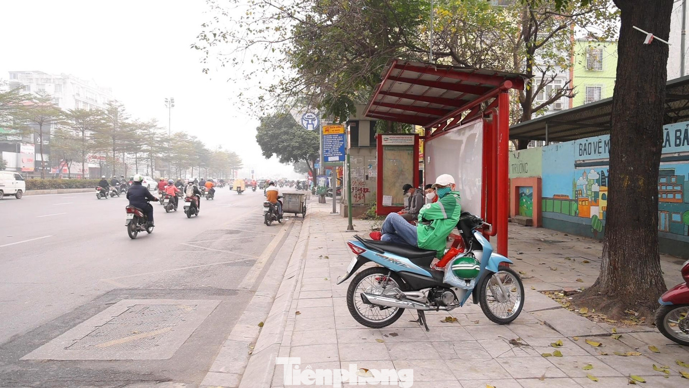Những người hoạt động trong lĩnh vực xe ôm công nghệ ngồi chờ khách tại 1 bến xe buýt.