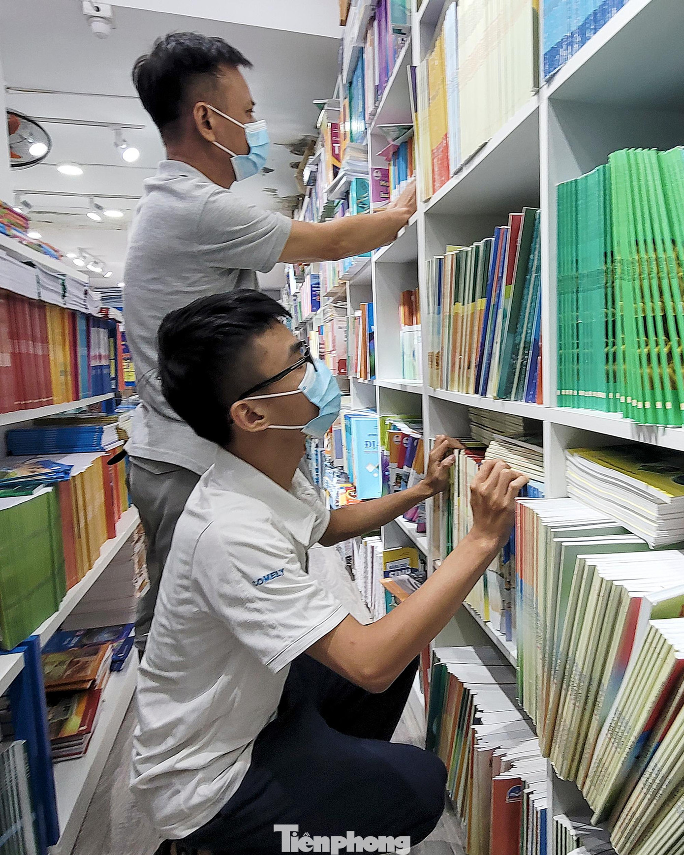 Hai bố con anh Nam (quận Đống Đa) cố tìm đủ bộ sách giáo khoa lớp 10 cho năm học mới tại một nhà sách.