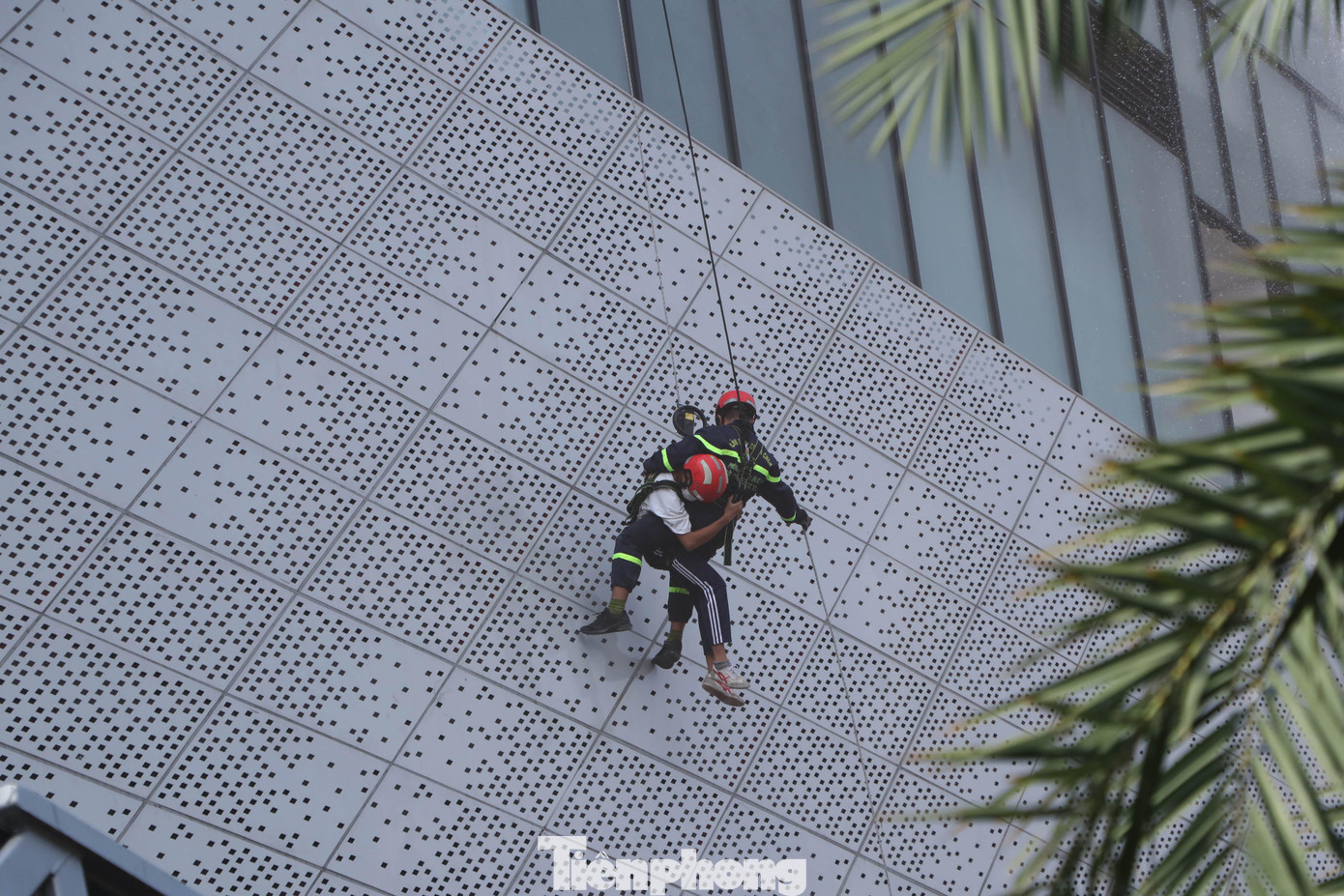 Lính cứu hỏa thực hiện cứu người bằng xe thang, ròng rọc đu dây từ trên sân thượng của tòa nhà xuống để giải cứu người mắc kẹt.