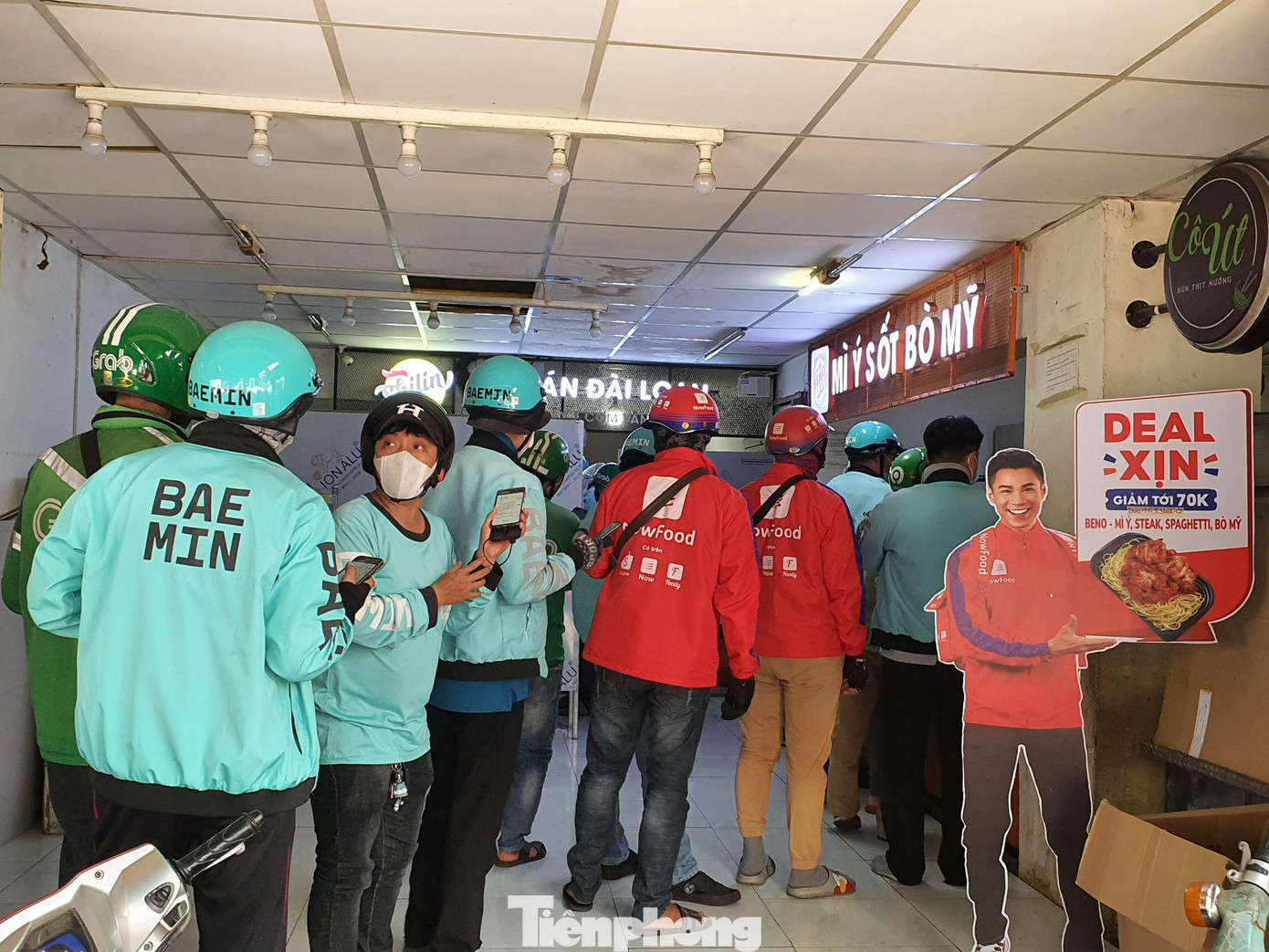 Các quán ăn không phục vụ tại chỗ, người dân phải mua mang về hoặc đặt hàng qua các dịch vụ giao hàng. Nhờ đó, shipper trở nên đắt khách. Trong ảnh: Shipper đứng xếp hàng dài ở các quán bán đồ ăn để nhận thức ăn cho khách.