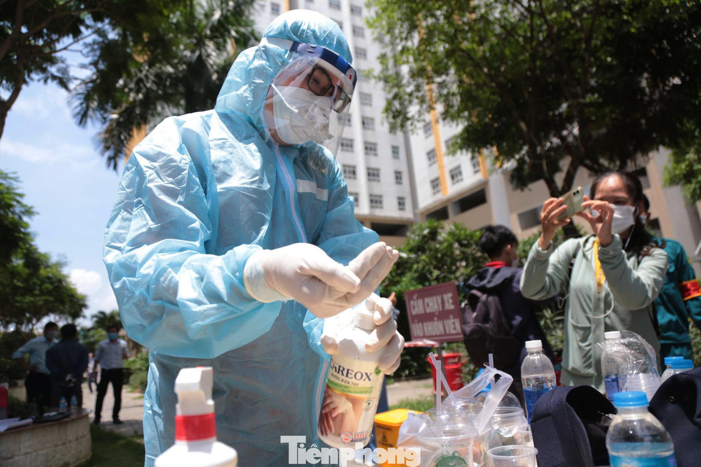 Bên trong khu vực chung cư, nhân viên y tế được trang bị bảo hộ kín mít từ đầu đến chân đang tiến hành lấy mẫu xét nghiệm COVID-19 cho toàn bộ cư dân, bảo vệ làm việc trong chung cư.