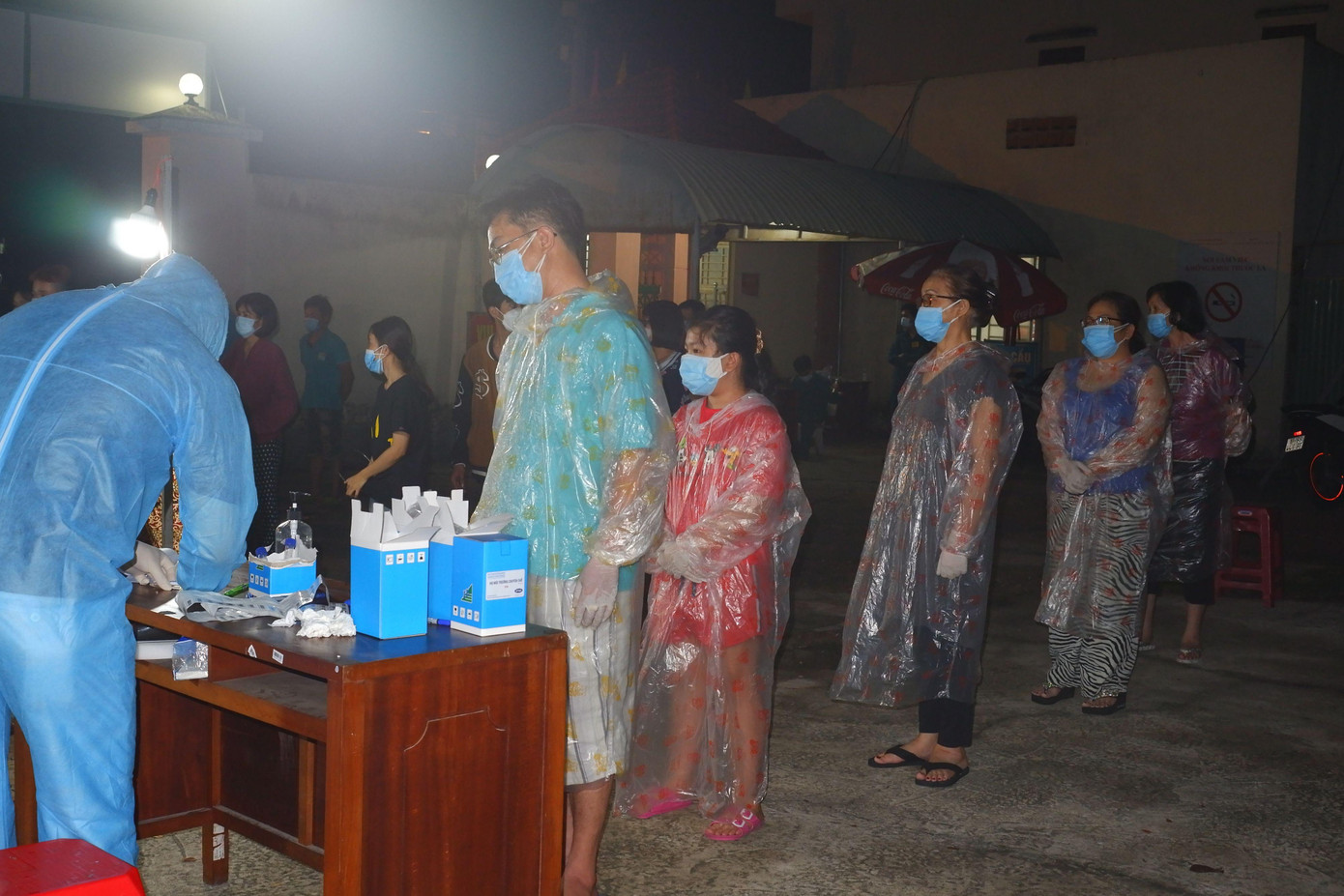 Không có đồ bảo hộ, một gia đình 5 người gồm bố mẹ và các con mặc áo mưa loại sử dụng một lần để phòng dịch đứng xếp hàng đợi lấy mẫu gộp lúc giữa khuya.
