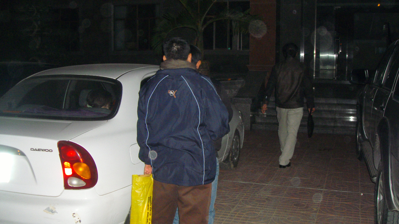 Người xách túi màu vàng là thân nhân, đang cố gắng che chắn cho ông Thắng, tránh bị chụp ảnh