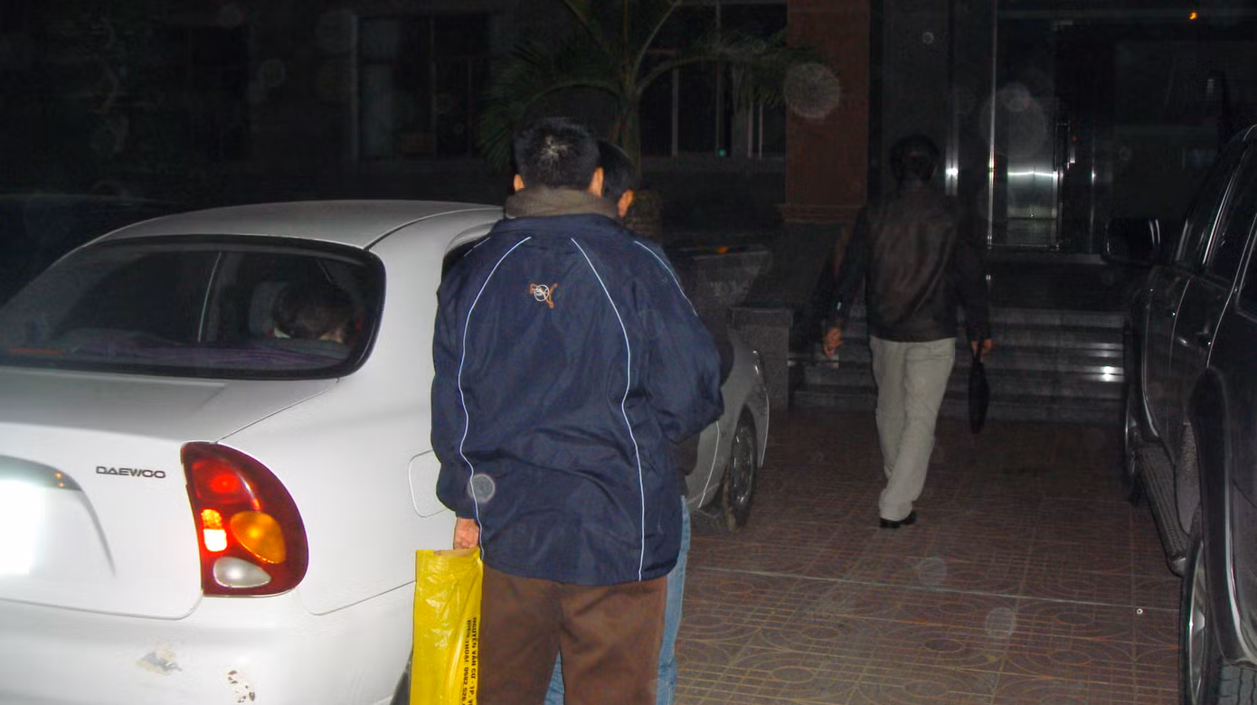 Người xách túi màu vàng là thân nhân, đang cố gắng che chắn cho ông Thắng, tránh bị chụp ảnh