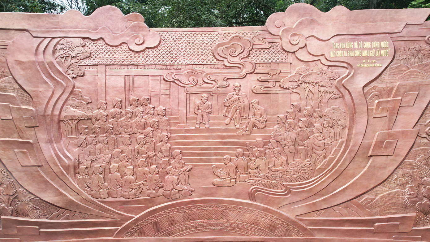 Phù điêu được tạo tác bằng chất liệu đồng dựa trên nền khung bê tông, cốt thép. Công trình cao 10m, rộng 27m, mô tả cuộc nói chuyện của Bác Hồ với Đại đoàn quân Tiên Phong năm 1954 tại Đền Giếng.