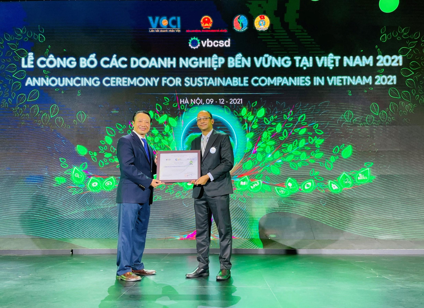 Ông Nguyễn Quang Vinh, Tổng thư ký VCCI, Phó Chủ tịch điều hành VBCSD (bìa trái), chúc mừng Ông Anand Jakati- Giám Đốc Chuỗi cung ứng, đại diện công ty Mondelez Kinh Đô, được vinh danh Top 100 doanh nghiệp bền vững tại Việt Nam năm 2021 Ông Nguyễn Quang Vinh, Tổng thư ký VCCI, Phó Chủ tịch điều hành VBCSD (bìa trái), chúc mừng Ông Anand Jakati- Giám Đốc Chuỗi cung ứng, đại diện công ty Mondelez Kinh Đô, được vinh danh Top 100 doanh nghiệp bền vững tại Việt Nam năm 2021