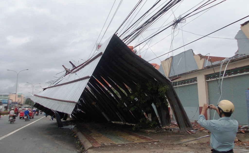 Toàn bộ mái nhà của dãy ki ốt thuộc công ty Xổ số Bình Dương nằm trên Đại Lộ Bình Dương (phường Hiệp Thành) bị hất tung ra đường, đè lên dây điện