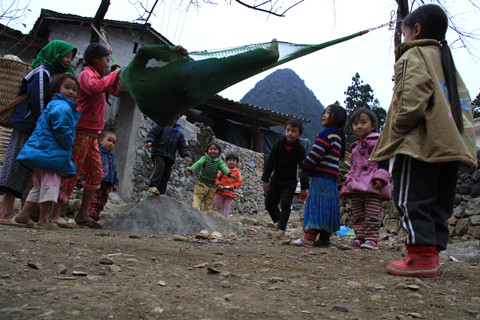 Không có trò chơi, chiều tối, lũ trẻ gần chợ Sà Phìn (xã Sà Phìn, Đồng Văn, Hà Giang) rủ nhau buộc một chiếc võng, lần lượt từng đứa ngồi lên võng và được bạn đung đưa. Chiếc võng là là mặt đất, sát ngay tảng đá hộc. Ảnh: Trường Phong. 