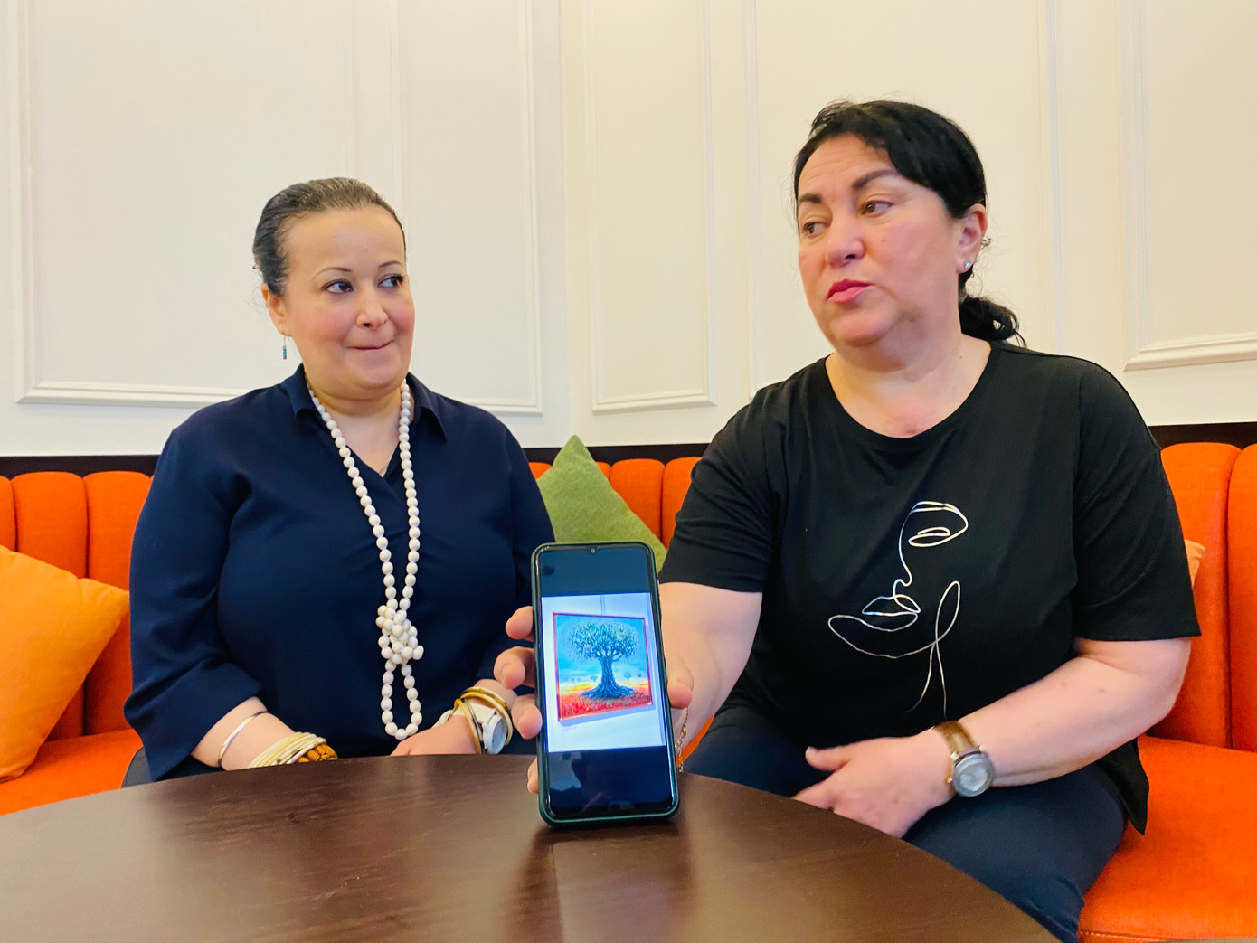 Họa sĩ Badia Maidat (phải) giới thiệu bức tranh “Sự kiên cường” sau khi em gái Siham Maidat kể về mẹ. Ảnh: Thái An. Họa sĩ Badia Maidat (phải) giới thiệu bức tranh “Sự kiên cường” sau khi em gái Siham Maidat kể về mẹ. Ảnh: Thái An.