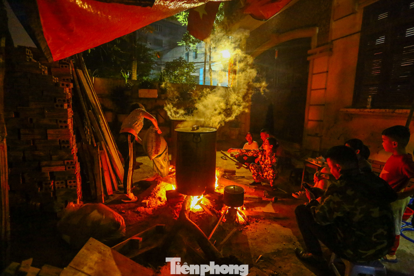 Chị Hồng Tâm cùng với gia đình gồm ba thế hệ nhiều con cháu cùng nhau thức canh nồi bánh chưng, bếp lửa hồng tại một góc sân trong ngõ 342 Khương Đình (quận Thanh Xuân, Hà Nội). Năm nay gia đình chị nấu khoảng hơn 200 cái bánh chưng.