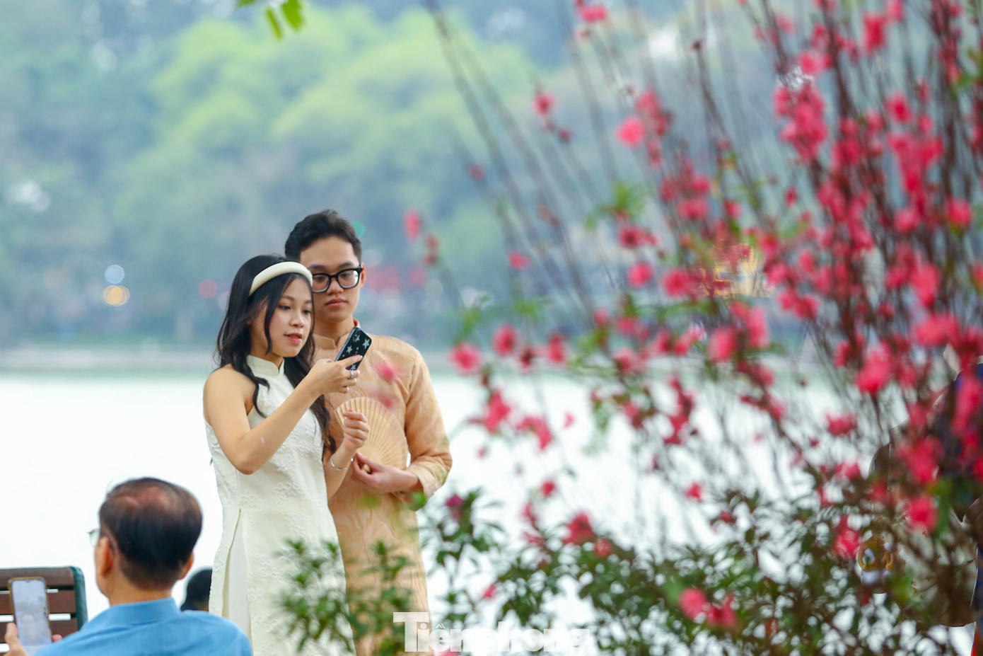 Các "nàng thơ" xúng xính trong các bộ trang phục truyền thống, tạo dáng chụp hình đón chào mùa xuân mới bên những cây đào quanh hồ.