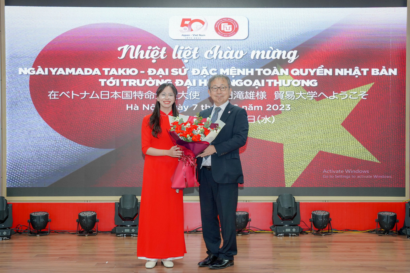 Đại diện sinh viên Trường Đại học Ngoại thương trao tặng bó hoa tươi thắm thay lời cảm ơn tới Ngài đại sứ Yamada Takio.
