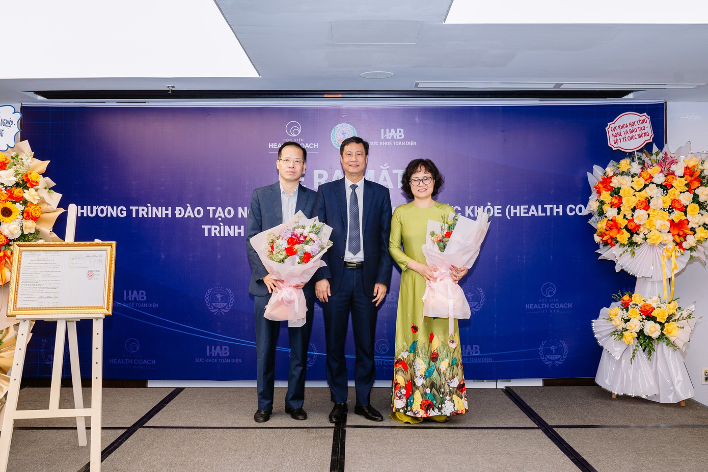 Tiến sĩ Trần Bá Kiên - Hiệu trưởng nhà trường tặng hoa cảm ơn các vị đại diện lãnh đạo 2 Bộ: Tiến sĩ Trịnh Văn Hùng, Trưởng phòng Quản lý Đào tạo, Cục KHCN và ĐT – BYT ( bên trái ảnh) và PGS. TS Nguyễn Thị Việt Hương – Phó Tổng Cục trưởng Tổng cục Giáo dục Nghề nghiệp – Bộ LĐTB&amp;XH (bên phải ảnh).