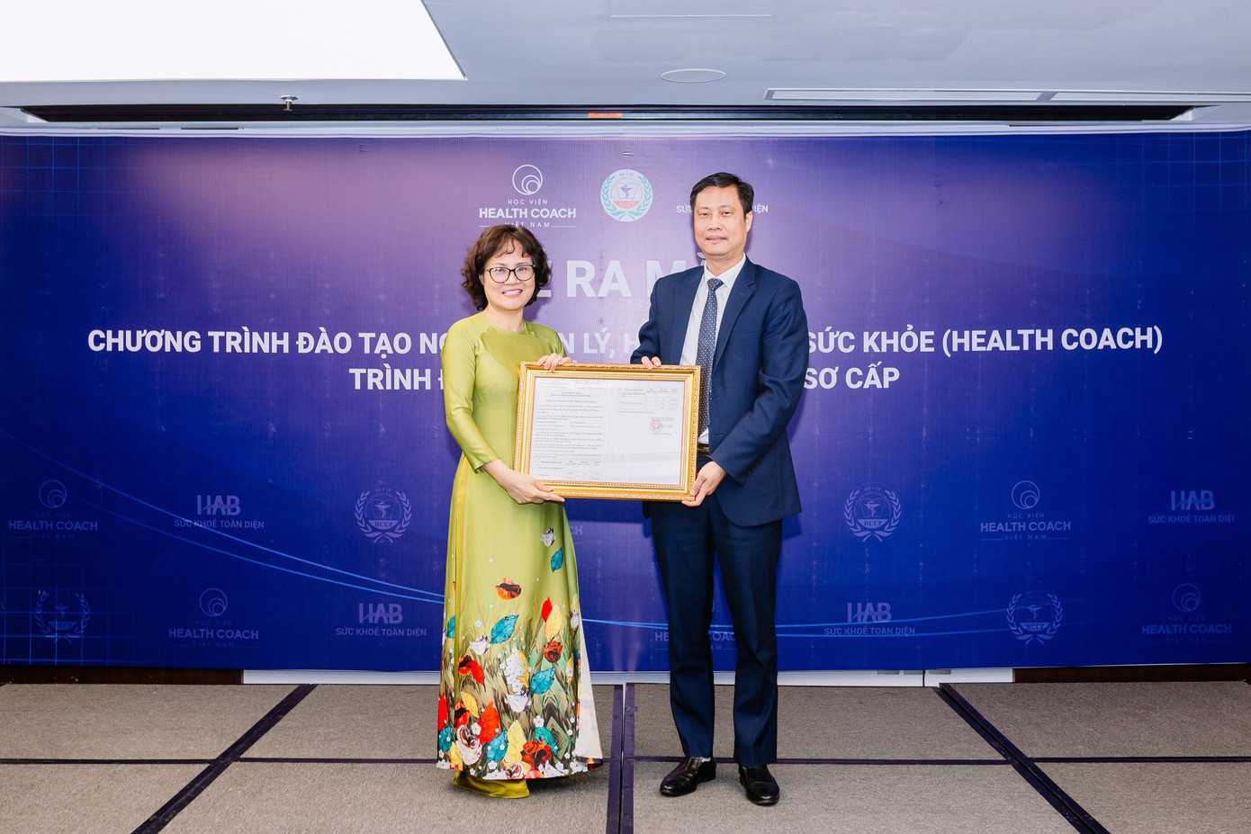 PGS.TS Nguyễn Thị Việt Hương – Phó Tổng Cục trưởng Tổng cục Giáo dục Nghề nghiệp – Bộ LĐTB&amp;XH - trao giấy chứng nhận hoạt động đào tạo nghề Quản lý huấn luyện sức khỏe cho Tiến sĩ Trần Bá Kiên – Hiệu trưởng nhà trường.