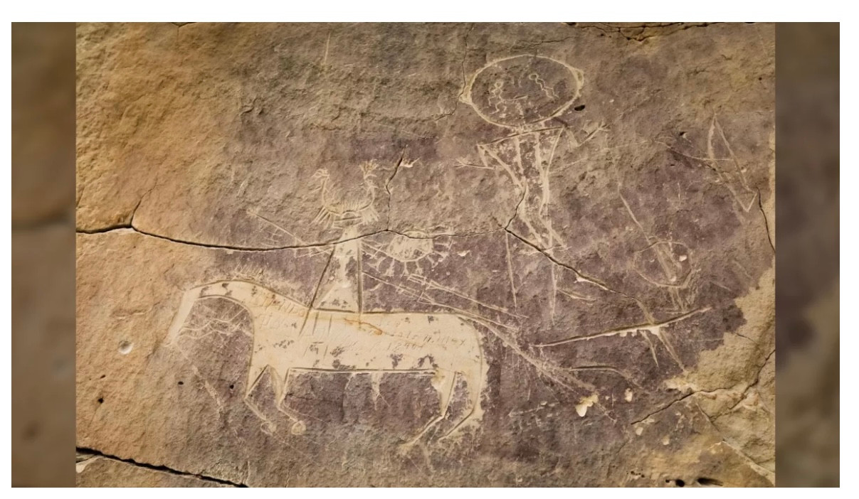 Một bức tranh khắc trên đá màu nâu xám mô tả một con ngựa và người cưỡi ngựa