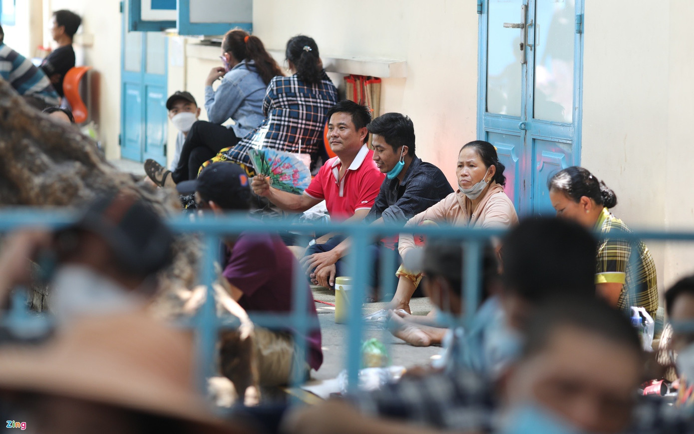 Anh Khánh (áo đỏ) cùng các thân nhân bệnh nhi khác vừa quạt, vừa trò chuyện trong bóng mát ở khuôn viên bệnh viện. Ảnh: Quỳnh Danh.