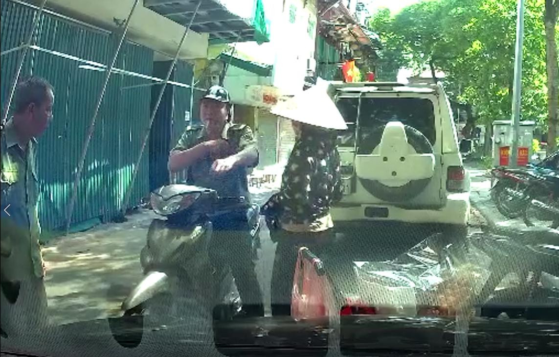 Người phụ nữ bán hàng rong đưa vật giống tiền cho cán bộ tự quản phường.