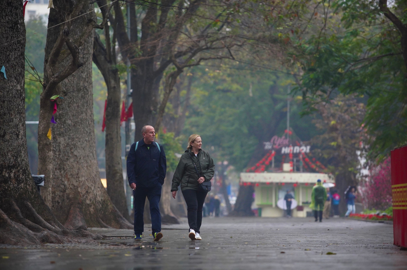 Khách tây dạo bước bên hồ Hoàn Kiếm trong thời tiết mưa phùn gió bấc.