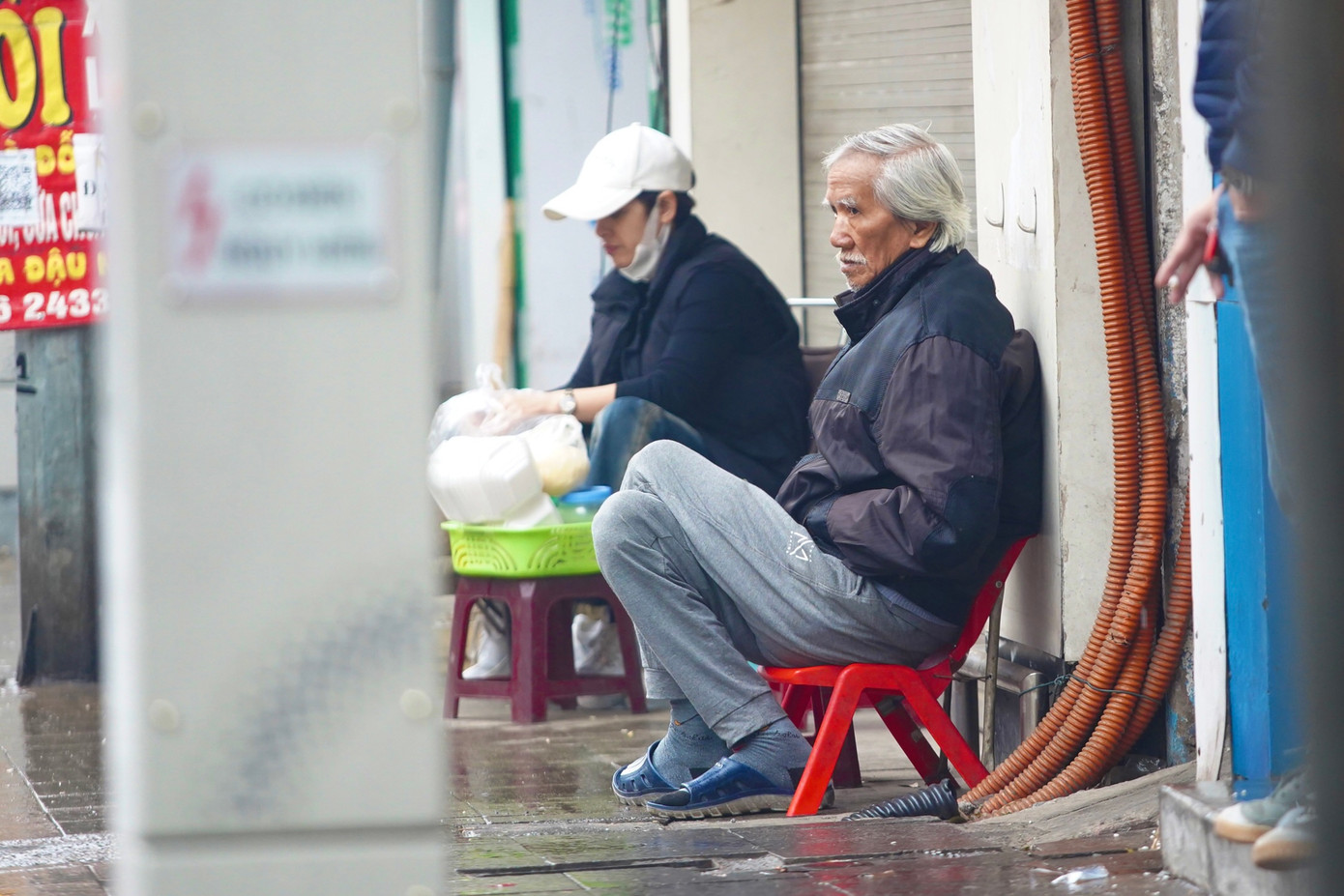 Người đàn ông lớn tuổi ngồi co ro trên phố Tây Sơn.