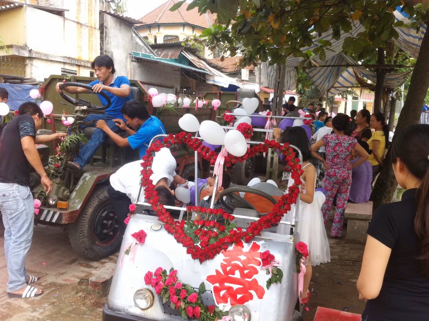 Chiếc xe điện màu trắng chú rể tự lái chở cô dâu và năm chiếc xe công nông chở hàng trăm khách