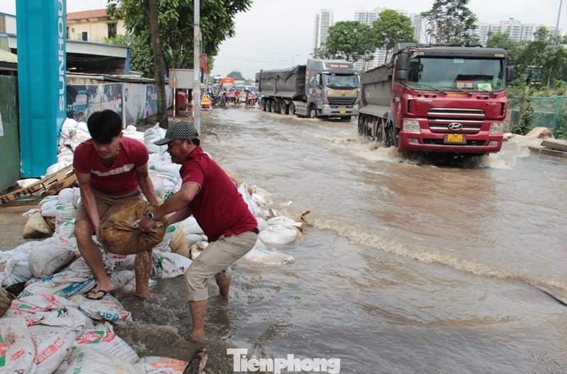 Nước ngập trên đường gom vẫn sâu và tạo sóng cao, có nguy cơ dâng vào nhà, một số hộ dân đã dùng bao tải cát làm bờ bao.