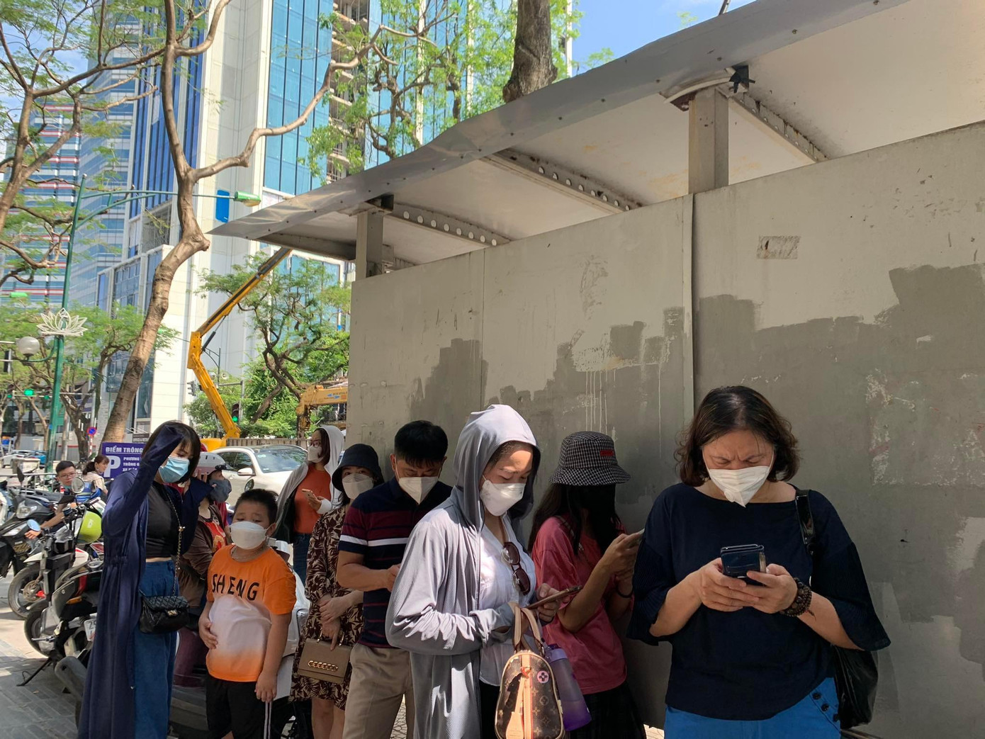 Nhiều phụ huynh tránh nắng ở sau điểm chờ xe buýt