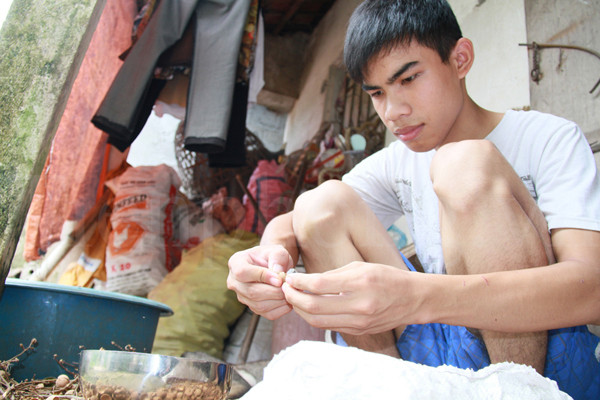 Phạm Văn Đích bóc long nhãn giúp mẹ. Hàng ngày, cậu đi xoáy nhãn thuê, mỗi ngày kiếm được khoảng 100 nghìn. Số tiền này, Đích tích trữ đề phòng mẹ đau yếu khi cậu nhập học. Ảnh: Trường Phong