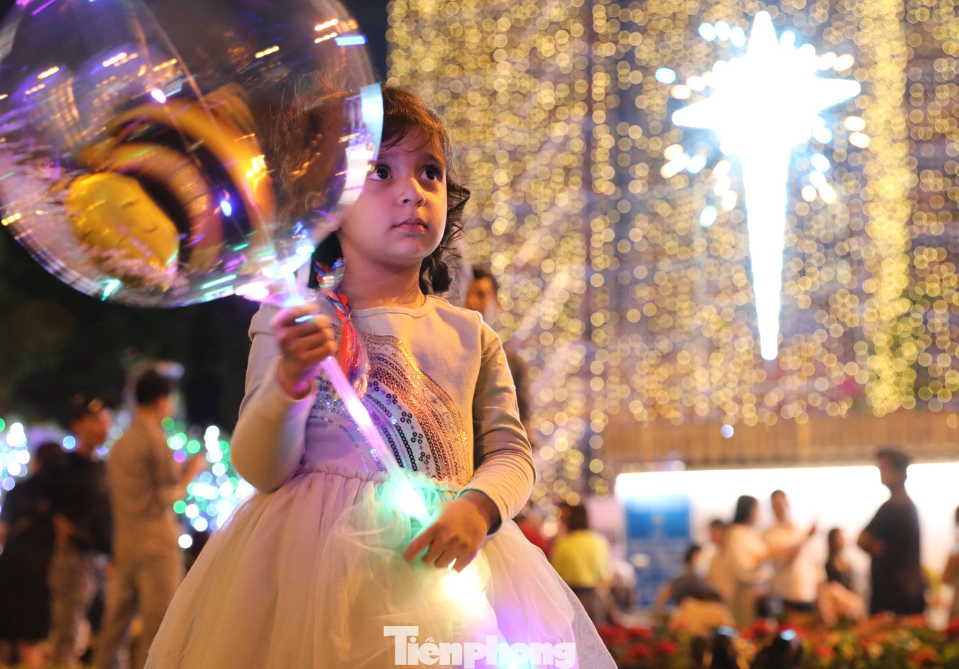 Một em bé người nước ngoài xuống phố vui chơi, hòa mình vào không khí nhộn nhịp đêm Giáng sinh.