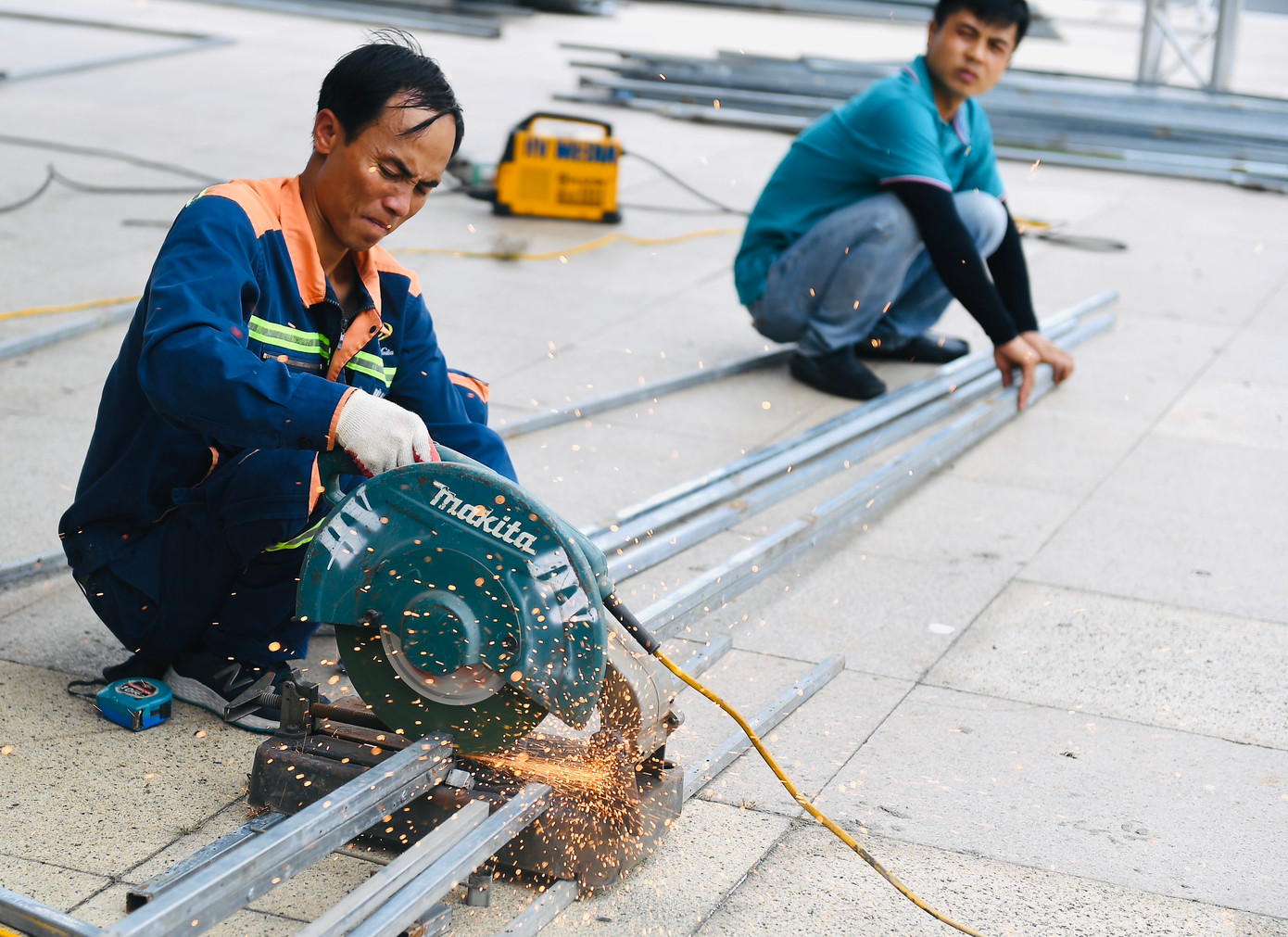 Phía trước sảnh sân vận động, các hạng mục như gian hàng quảng bá, khu vực khán giả xếp hàng kiểm soát vé để vào trong đang được gấp rút hoàn thành.