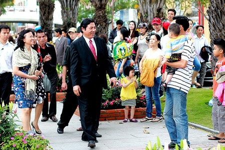 Ông nở nụ cười với một em nhỏ được bố bế trên tay . Ông nở nụ cười với một em nhỏ được bố bế trên tay