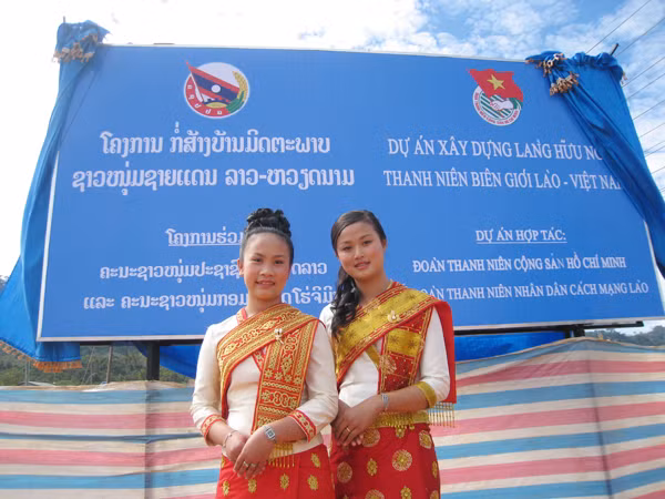 Hai thiếu nữ Lào bên tấm biển Dự án Làng Thanh niên Hữu nghị Biên giới Lào - Việt vừa được hai Bí thư thứ nhất cắm ở tỉnh Bolikhamxay