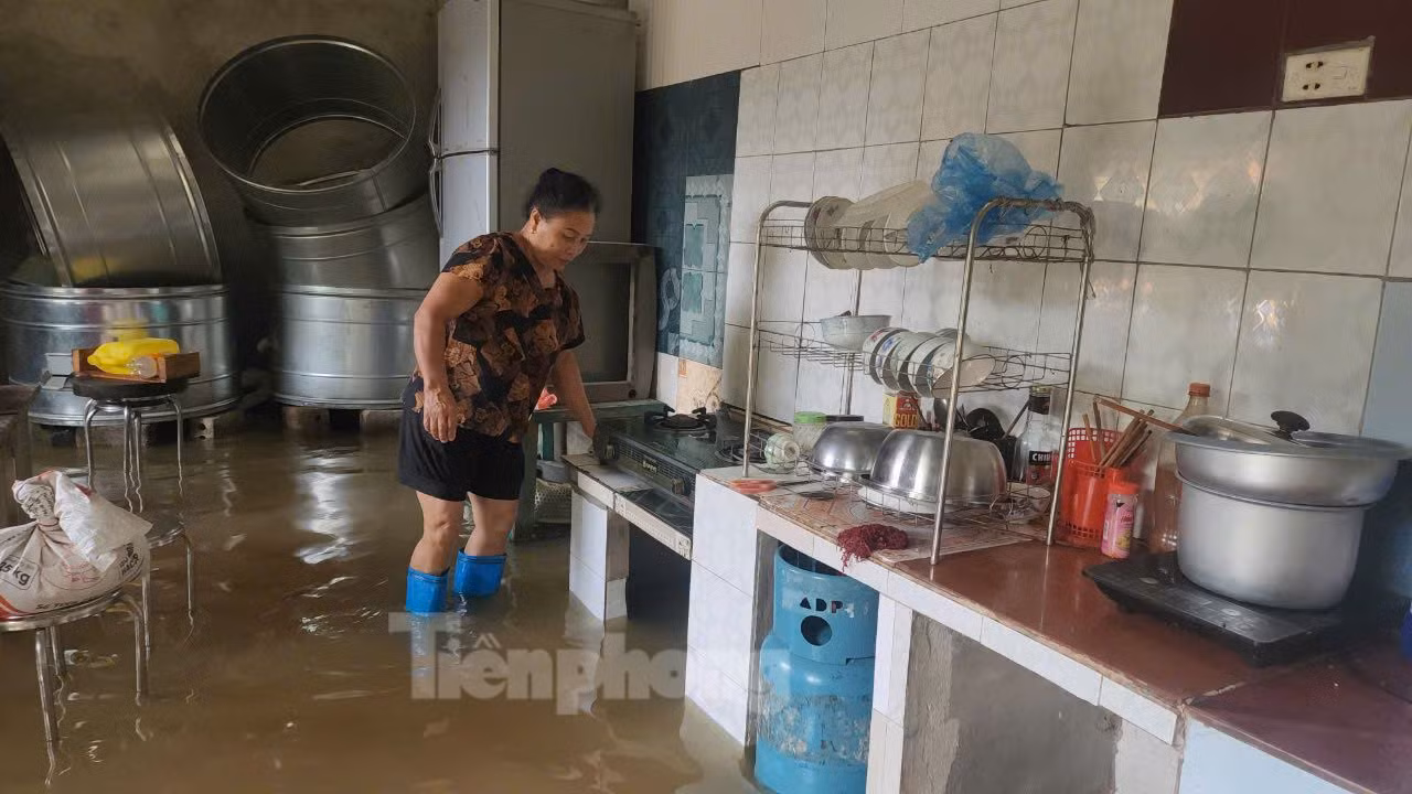 Bà Nguyễn Thị Nga (thôn Tiến Tiên) đang nấu cơm. Bà cho biết, nước sông Bùi lên rất nhanh. Hiện mực nước năm nay cao hơn đợt lũ năm 2018 đến 40cm và cao hơn đợt lũ tháng 7/2024 khoảng 60cm.