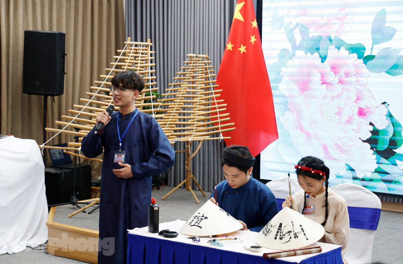 Các sinh viên thể hiện tài viết thư pháp bằng tiếng Việt và tiếng Trung trên nón lá. (Ảnh: Như Ý) Các sinh viên thể hiện tài viết thư pháp bằng tiếng Việt và tiếng Trung trên nón lá. (Ảnh: Như Ý)