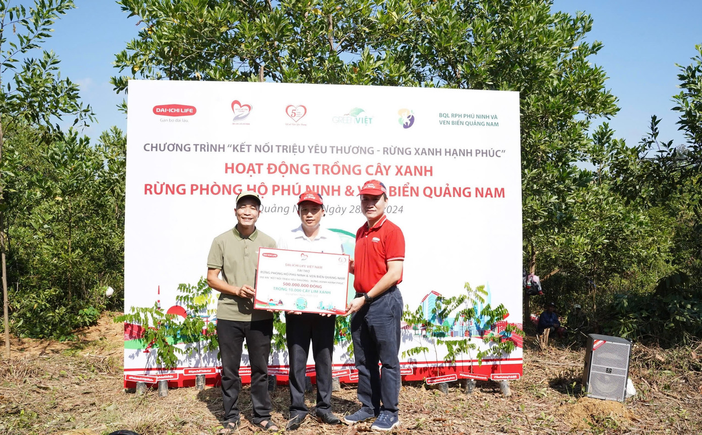 Ông Trần Đình Quân, Chủ tịch Hội đồng Thành viên Dai-ichi Life Việt Nam kiêm Chủ tịch Quỹ Vì cuộc sống tươi đẹp (áo đỏ)trao biểu trưng số tiền tài trợ 500 triệu đồng trồng 10.000 cây lim xanh cho Đại diện Ban Quản lý Rừng phòng hộ Phú Ninh và Green Việt