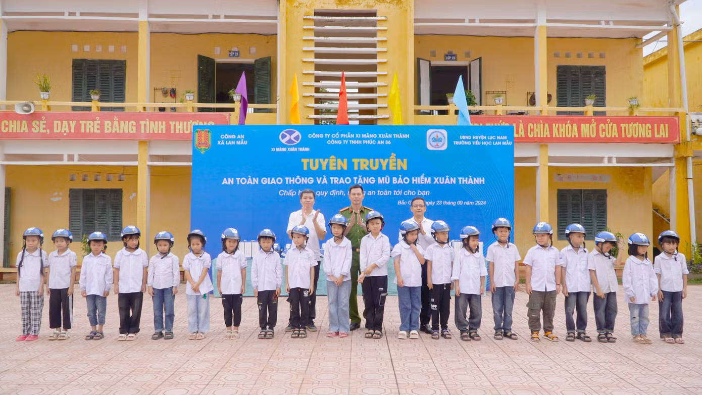Đại diện Xi Măng Xuân Thành trao tặng mũ bảo hiểm đạt chuẩn cho các em học sinh tại trường Tiểu học Lan Mẫu (huyện Lục Nam - Bắc Giang)
