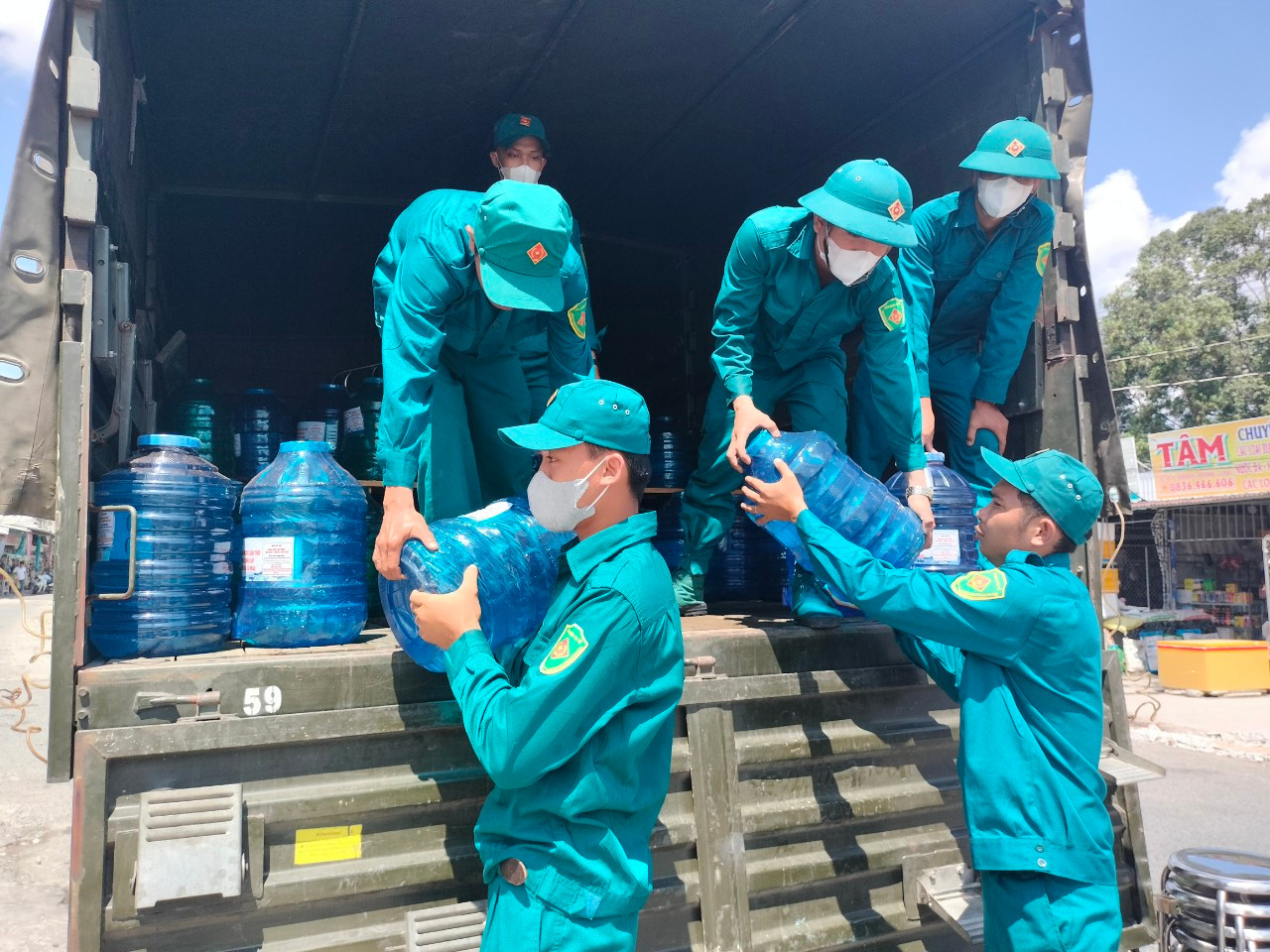 Lực lượng hỗ trợ mang bình nước lọc cung cấp cho người dân.