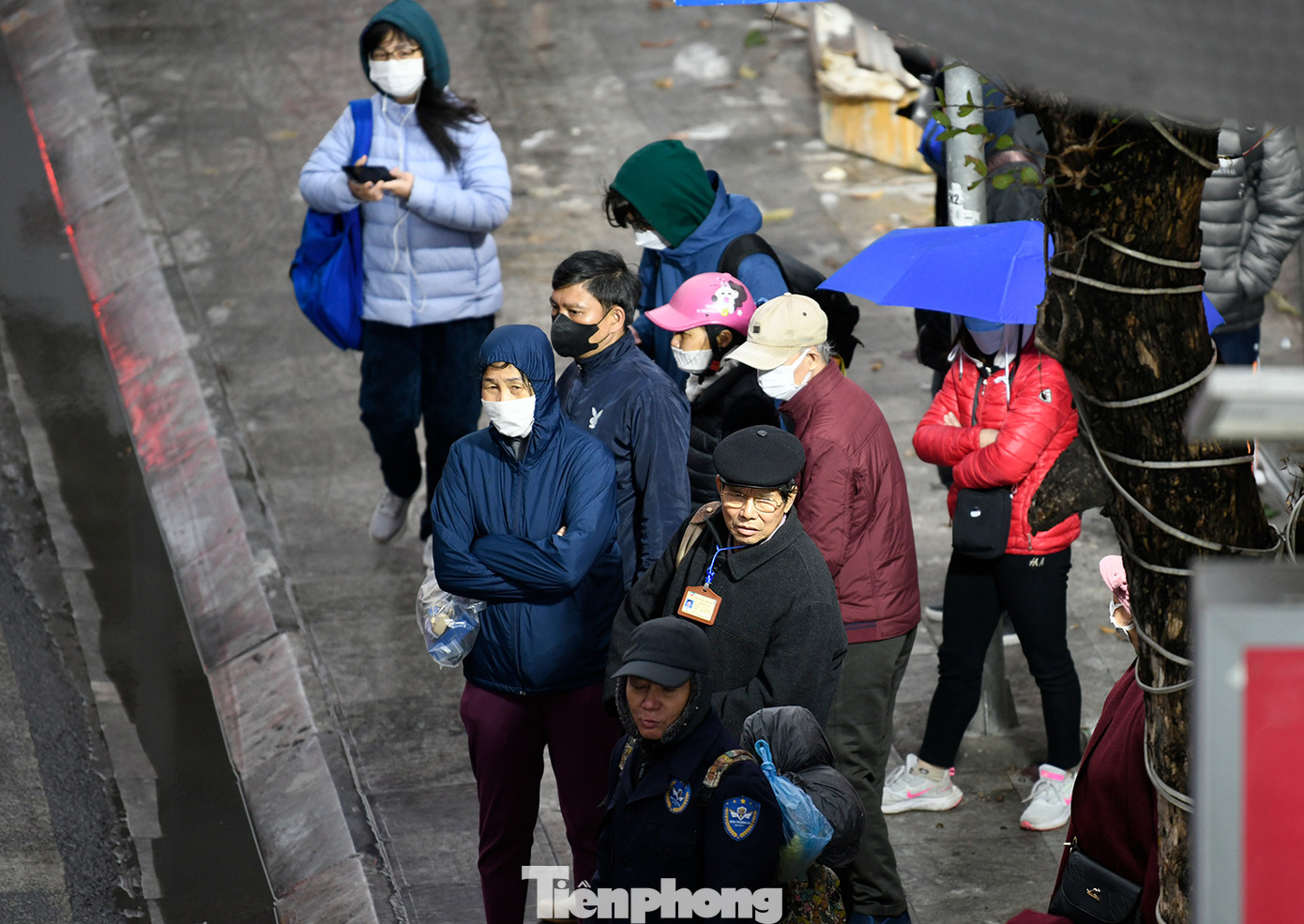 Mọi người trang bị áo ấm, khẩu trang, mũ và khăn khi đứng chờ xe buýt trên đường Nguyễn Trãi (quận Thanh Xuân).