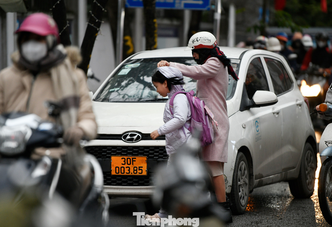 Bố mẹ đưa con đi học vào sáng sớm ngày hôm nay đều mặc áo ấm cho con khi đến trường.