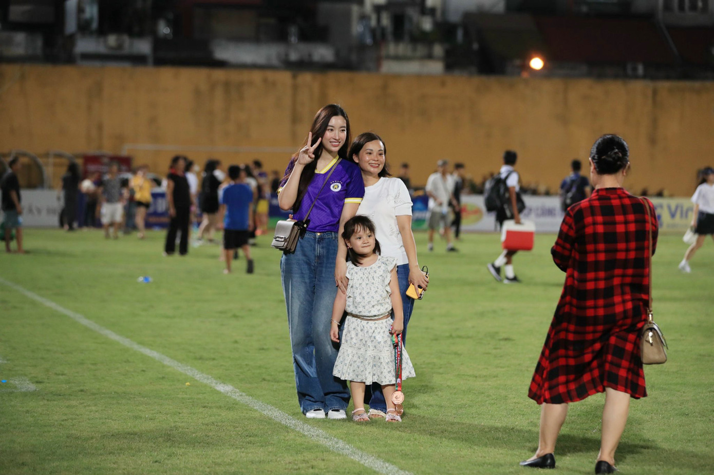 Đỗ Mỹ Linh chụp ảnh cùng khán giả tới theo dõi trận đấu. Cô ăn mặc giản dị khi phối áo đấu của CLB Hà Nội với quần jeans ống rộng. Người đẹp cũng trang điểm nhẹ nhàng, tự nhiên. Ảnh: Minh Dân.