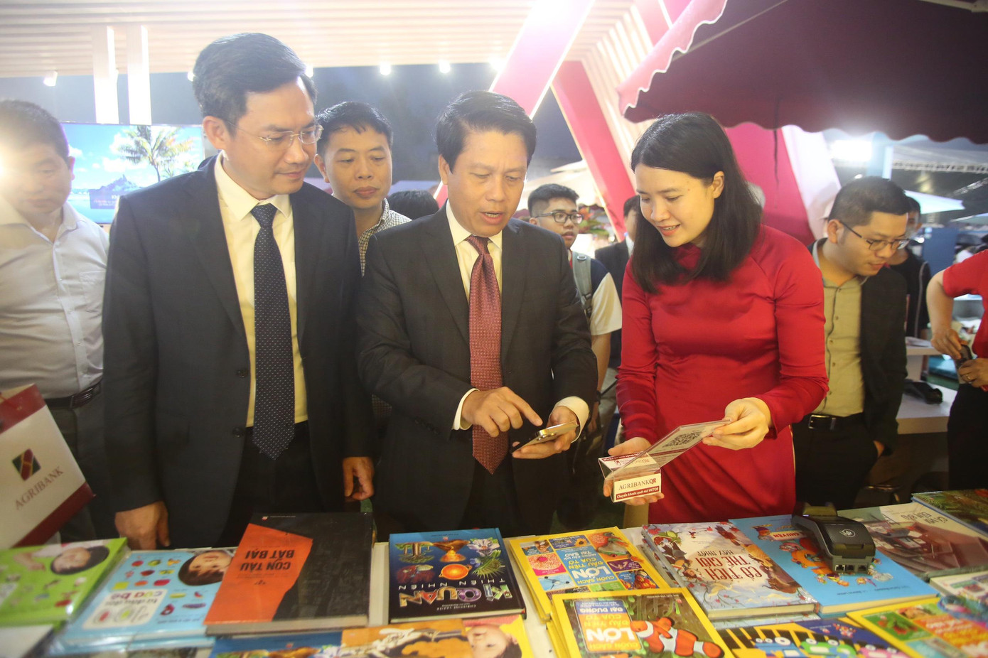 Phó Thống đốc thanh toán bằng quét mã VietQR tại gian hàng của Ngân hàng Agribank để mua sách. Phó Thống đốc mua 2 cuốn sách cho con trai bằng ap tài khoản trên điện thoại của mình.