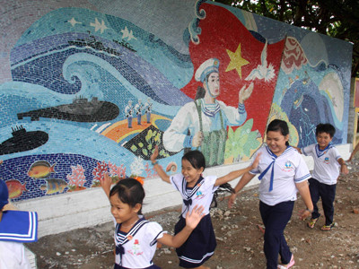 Trẻ nhỏ trên đảo chơi cạnh các bức tường gốm được xây dựng đồng thời với lá cờ. Ảnh: Tạ Ngọc Hưng (VOV) và Trần Việt (TTXVN) Trẻ nhỏ trên đảo chơi cạnh các bức tường gốm được xây dựng đồng thời với lá cờ