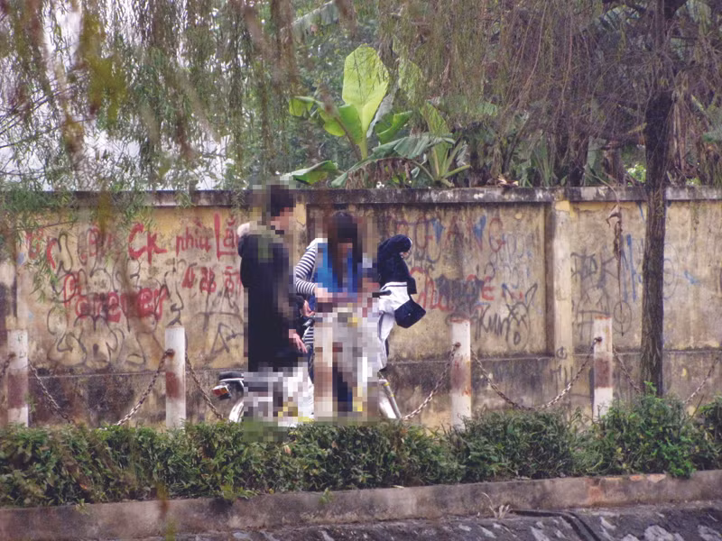 Ngồi tâm sự ở hồ Văn Quán đến sát giờ học, cô gái vội vàng lấy áo đồng phục, yêu cầu bạn trai chở về trường. Ảnh: Trường Phong