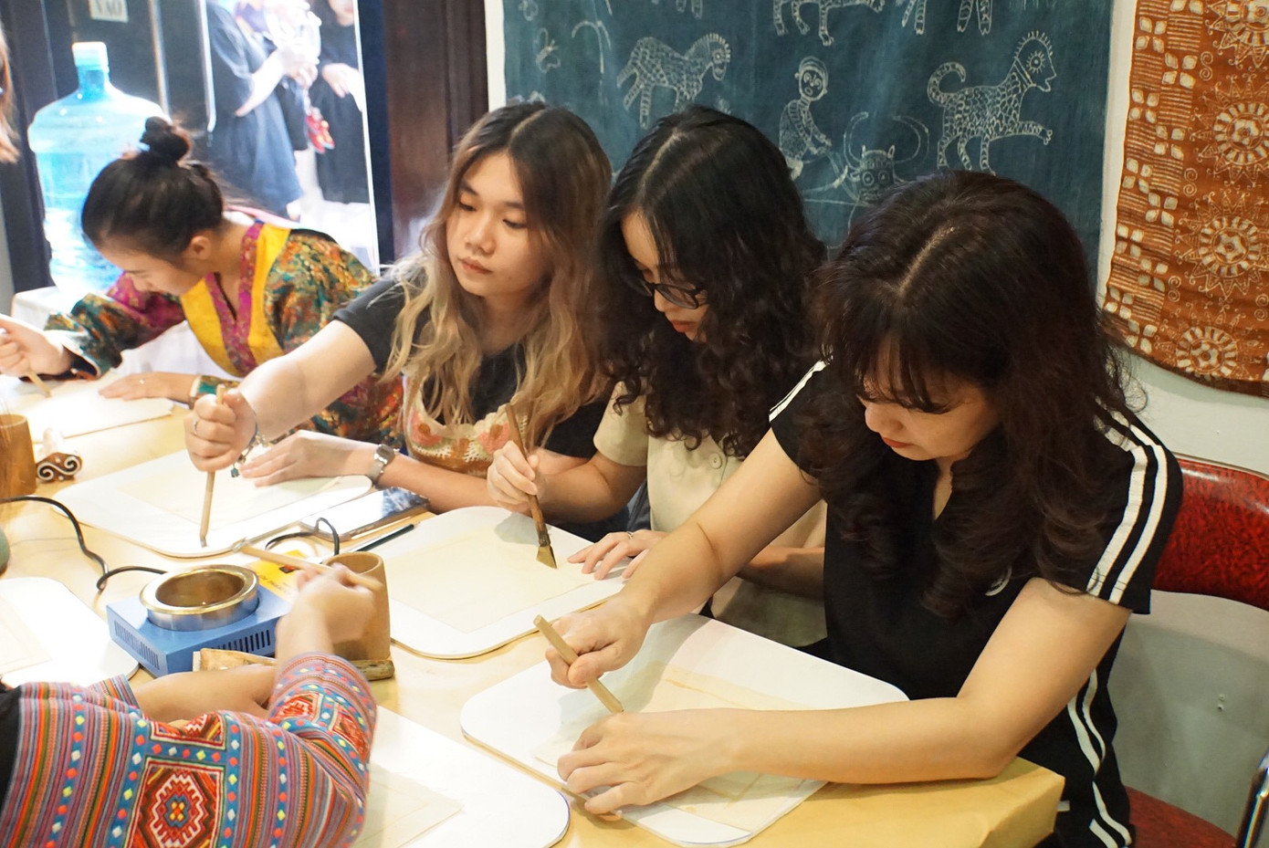 Một số bạn trẻ đang trải nghiệm kỹ thuật vẽ sáp ong trên vải tại sự kiện.