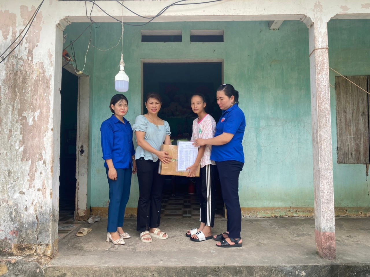 Đại diện gia đình và em Dương đón nhận quà tặng sách vở của năm học mới.