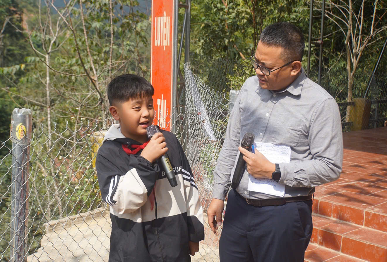 Nhà báo Hồ Sỹ Lực giao lưu, trò chuyện với một em học sinh của Trường Tiểu học xã Ca Thành. "Sau mưa bão, đất đá quanh nhà con sạt xuống nhiều lắm. Trường con đang học cũng bị sạt lở. Phải mấy ngày sau con mới được đi học lại", em học sinh chia sẻ.